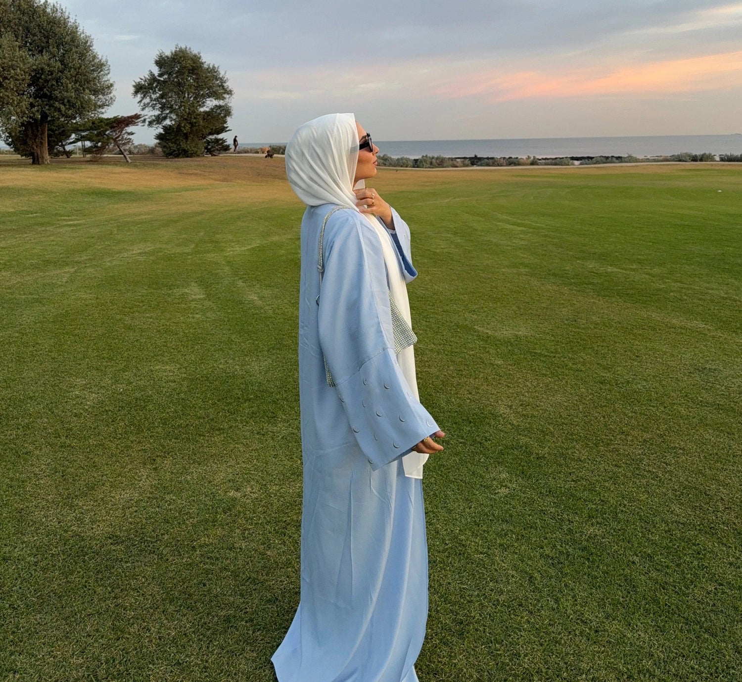 Classy trendy islamic clothing: light blue abaya and hijab styled outdoors at sunset