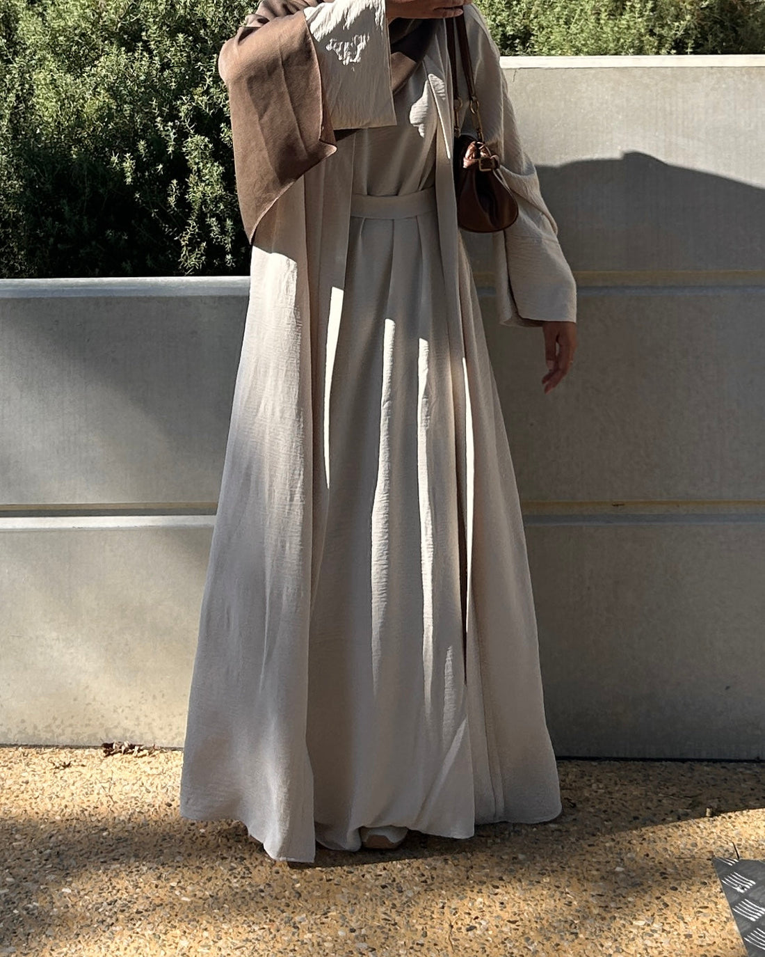 Woman wearing a flowing beige open abaya, everyday modest fashion style