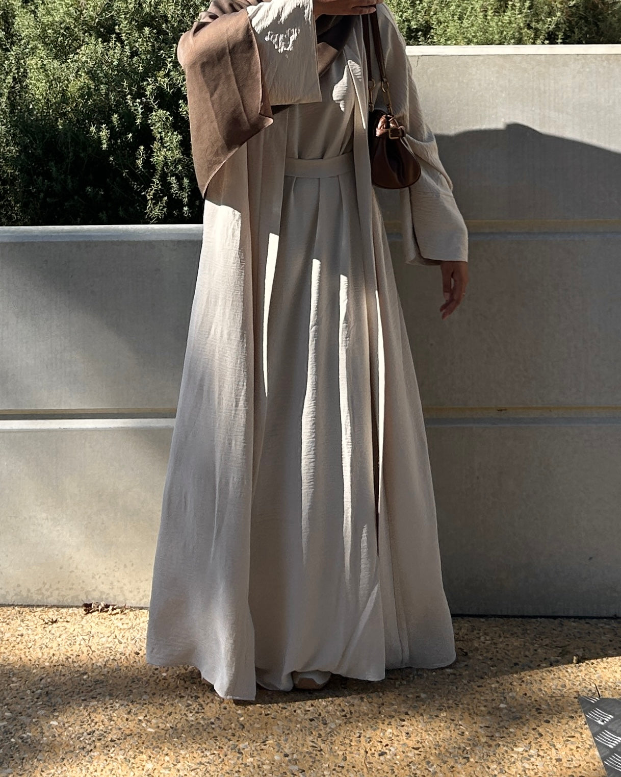 Woman wearing a flowing beige open abaya, everyday modest fashion style