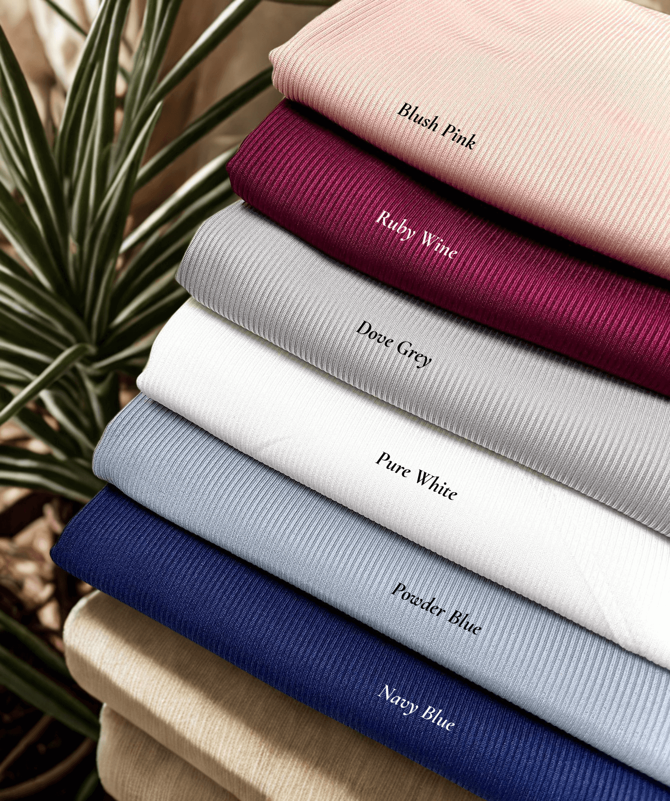 Flat lay of hijabs stacked including blush pink, ruby wine, dove grey, pure white, powder blue, navy blue textured jersey hijab – Qalbi