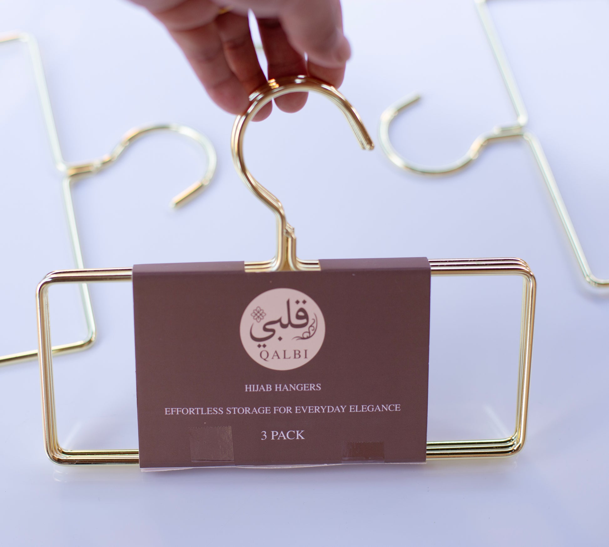 Hand holding a gold metal hanger, highlighting the smooth finish and sturdy frame.