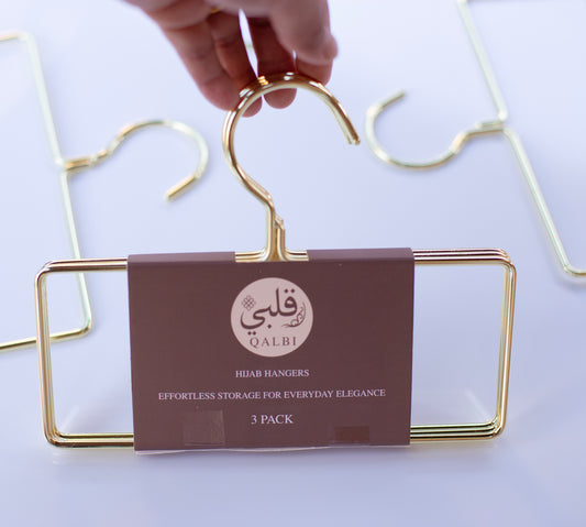 Hand holding a gold metal hanger, highlighting the smooth finish and sturdy frame.